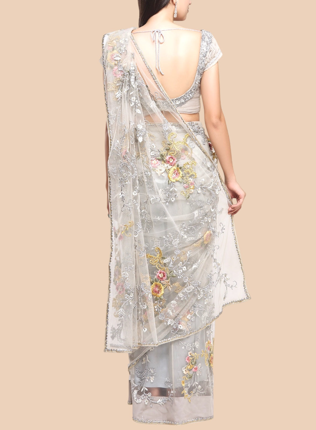 Woman wearing a floral embroidered saree with a plain background