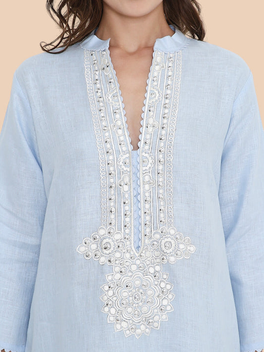 Light blue shirt with intricate white embroidery on a beige background