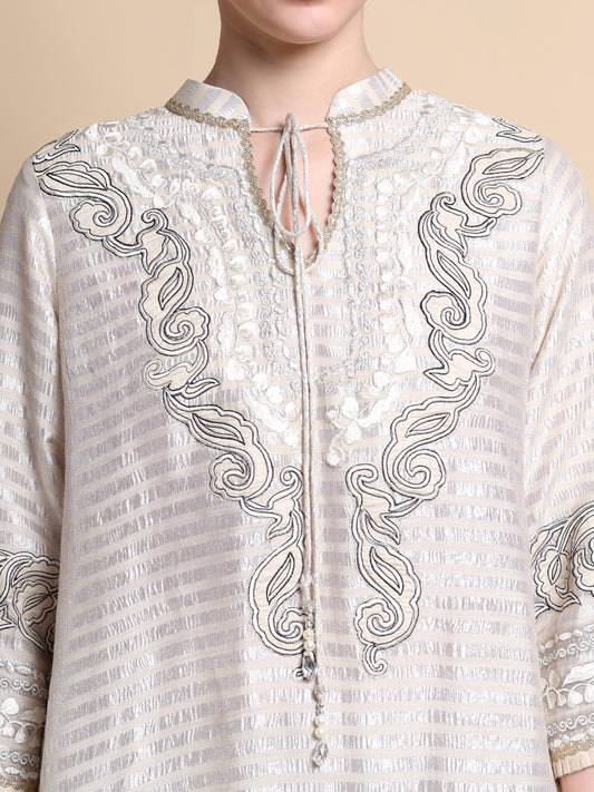 White embroidered shirt with intricate patterns on a beige background