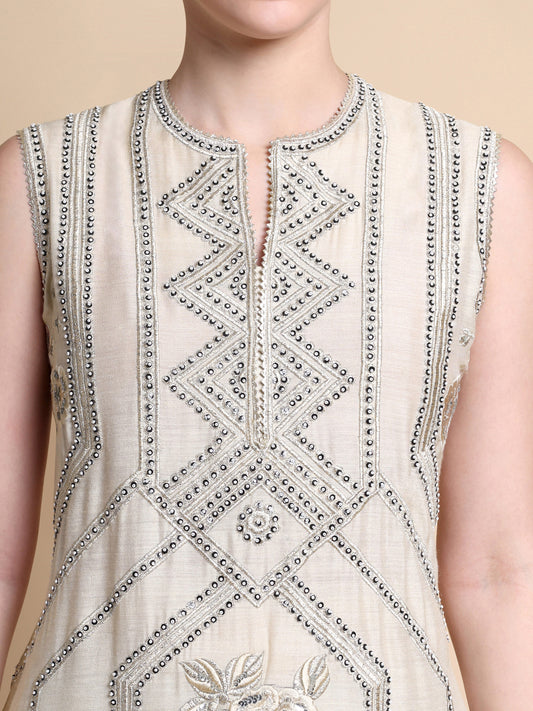 Close-up of a sleeveless top with intricate beadwork on a neutral background