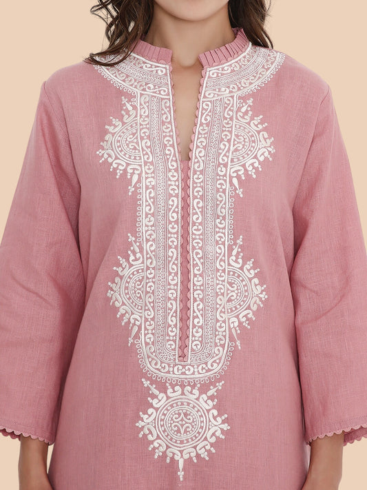 Pink embroidered dress with white patterns on a beige background