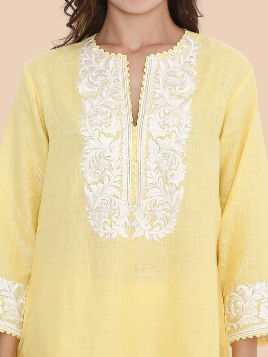 Yellow kurta with white lace details on a beige background