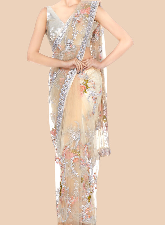 Woman wearing a floral embroidered saree with a plain background