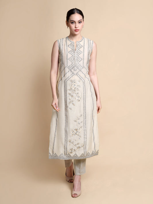 Woman wearing a beige sleeveless kurta with intricate patterns on a beige background