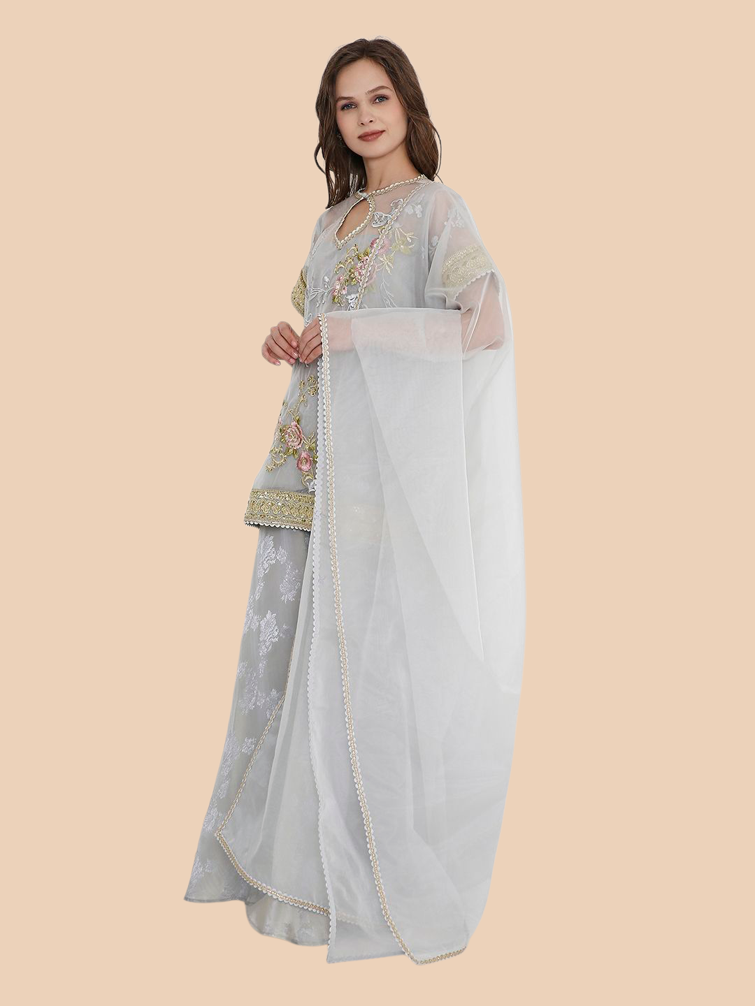 Woman wearing a light gray traditional outfit with embroidery on a beige background