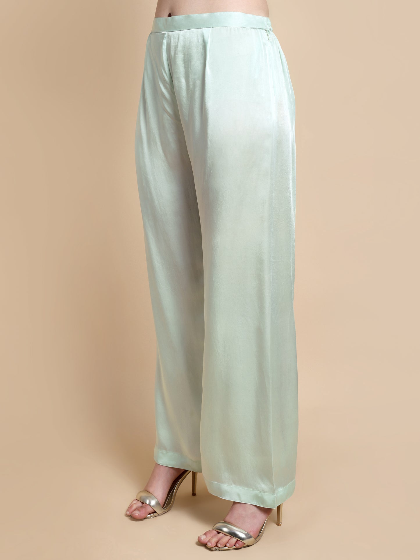 Light green wide-leg pants worn by a person on a beige background