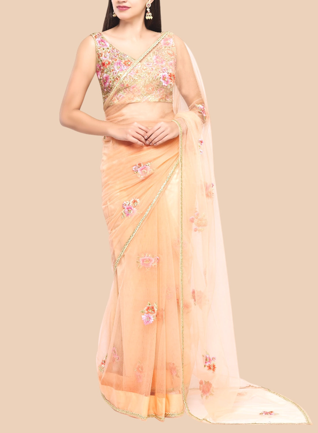 Luxurious peach net sari featuring floral embroidery, complemented by a sleeveless brocade blouse and unstitched petticoat.