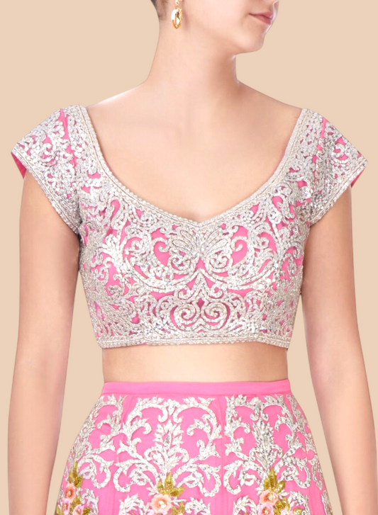 Woman wearing a pink and white embroidered blouse with a beige background