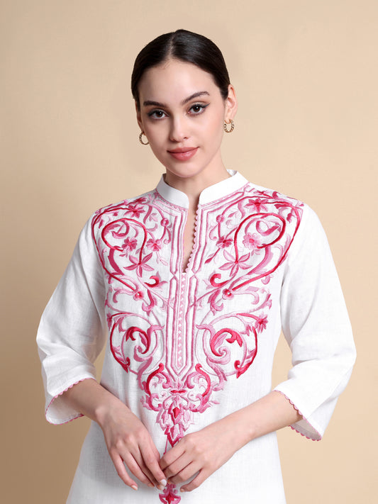 Woman wearing a white kurta with pink embroidery on a beige background