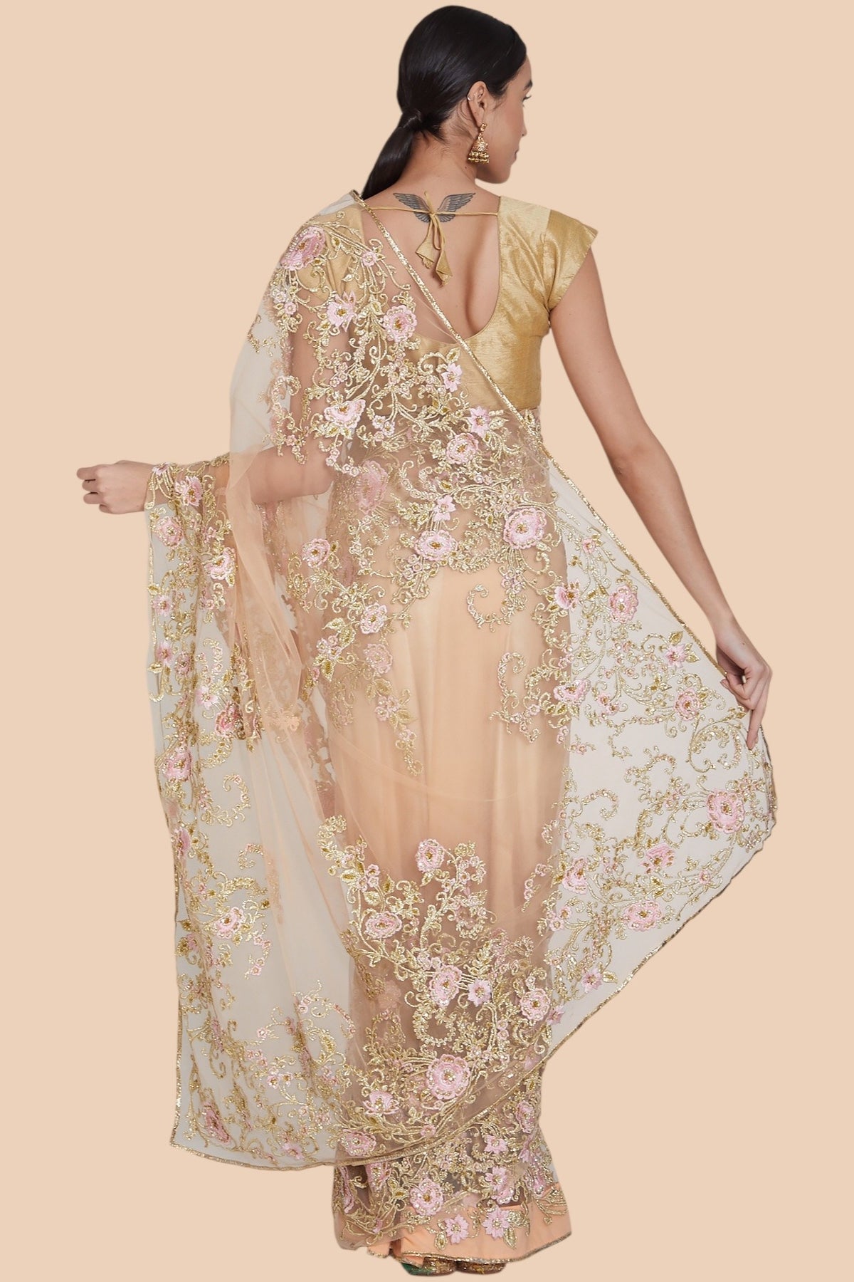 Full back look of peach net sari with matching blouse and accessories