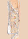 Beige saree with floral embroidery and silver border on a beige background