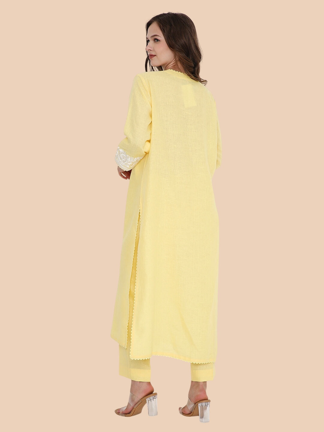 Woman wearing a light yellow kurta with a plain background