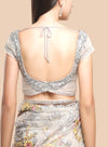 Woman wearing a silver embroidered blouse with a floral saree on a beige background
