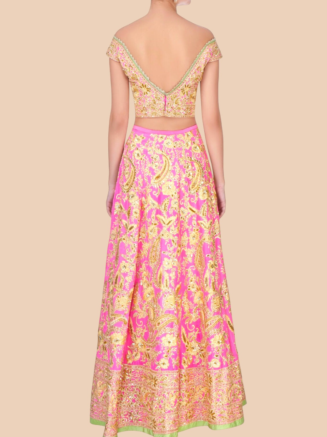 Pink and gold embroidered traditional outfit on a beige background