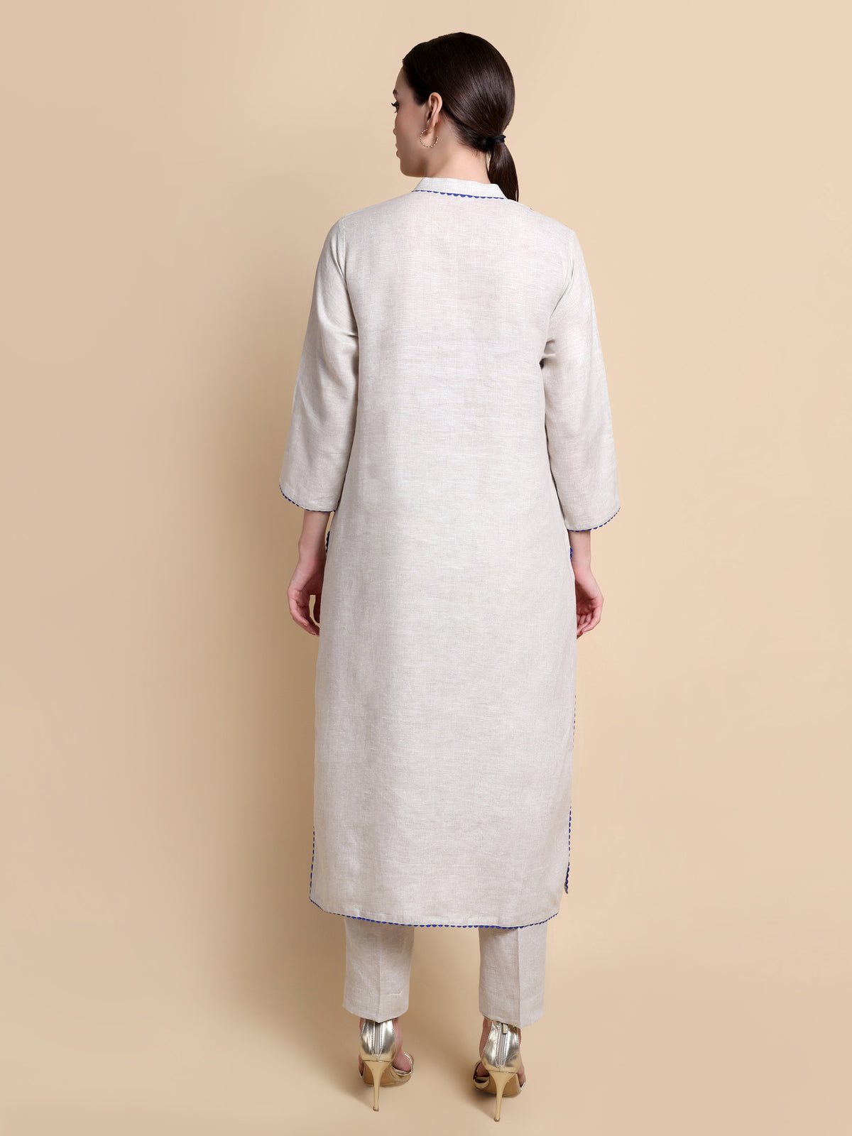 Woman wearing a light gray kurta with pants on a beige background