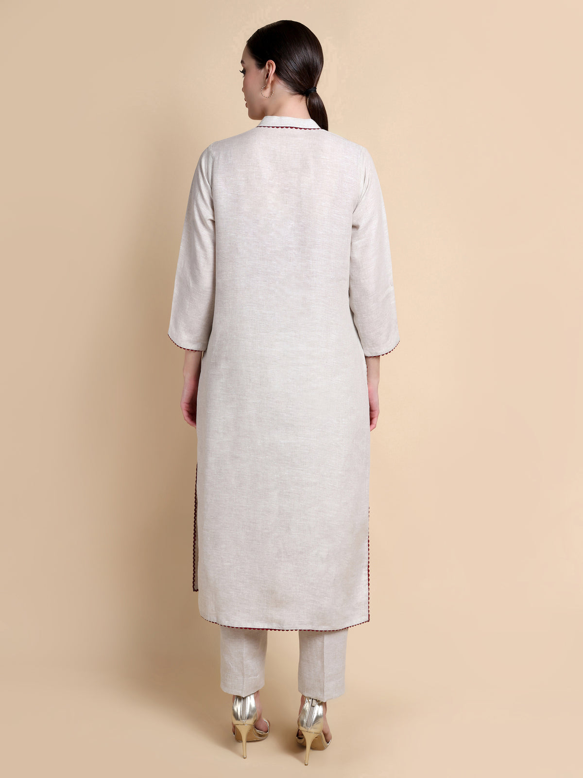 Woman wearing a light gray kurta with pants on a beige background