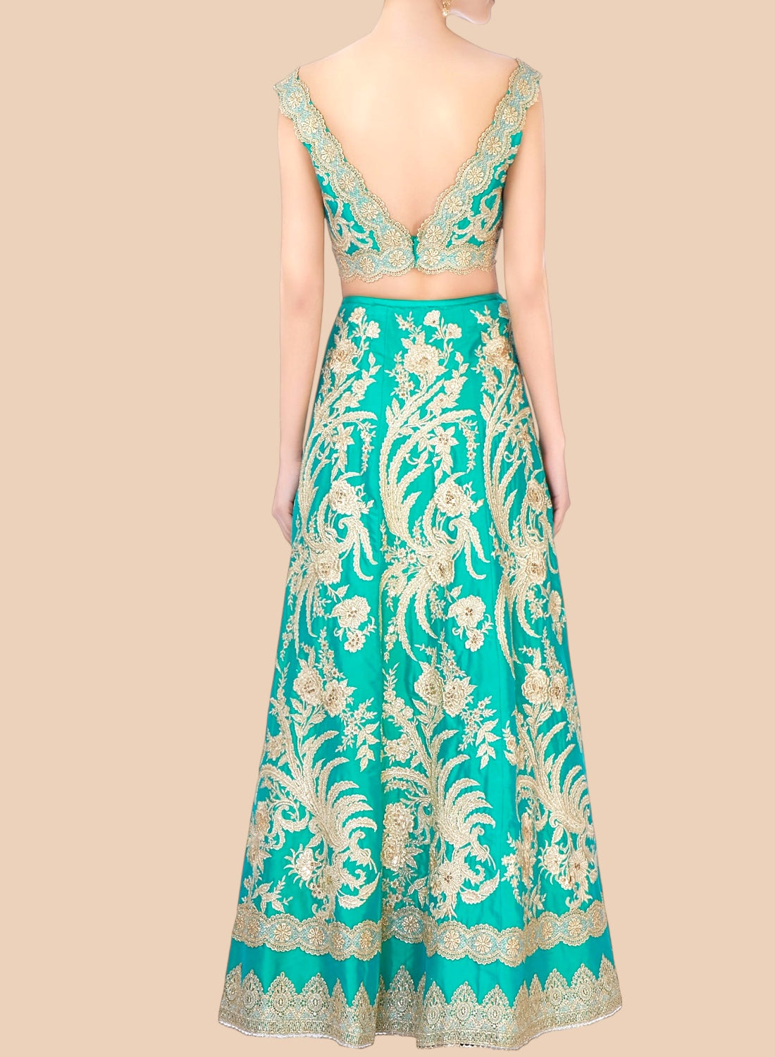 Teal embroidered dress with gold patterns on a beige background