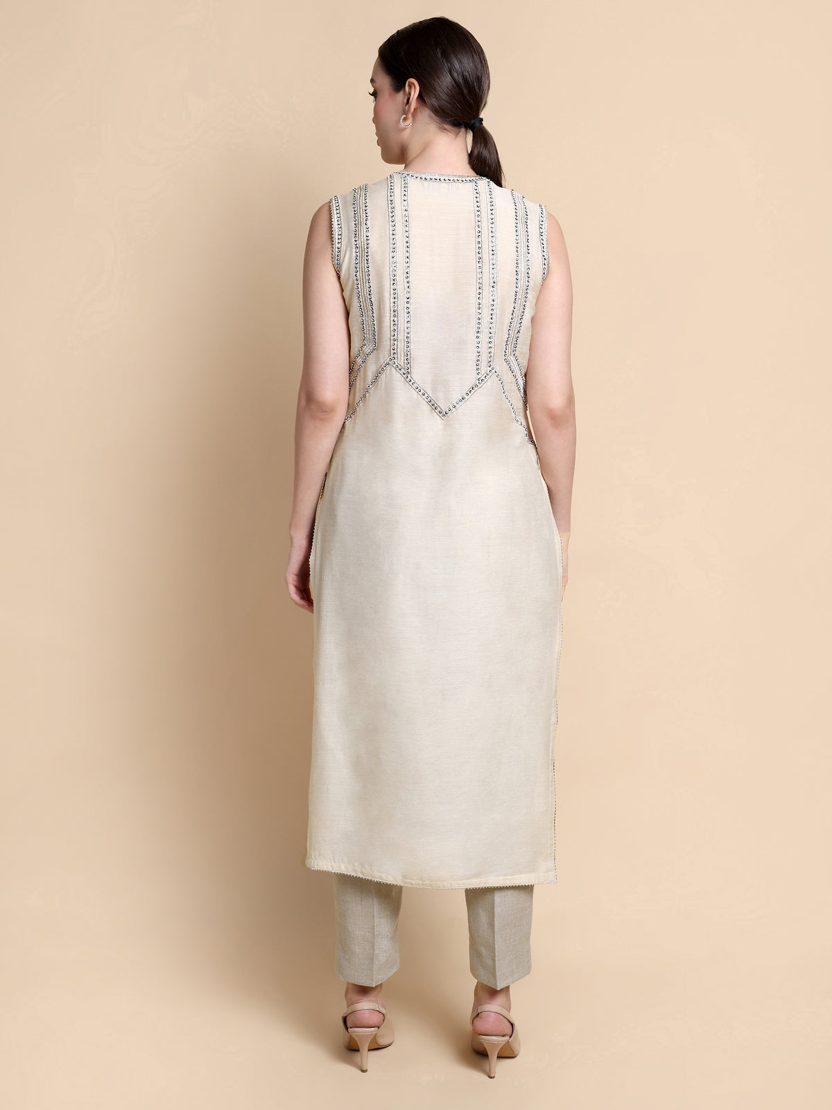 Woman wearing a cream-colored kurta with intricate detailing on a beige background