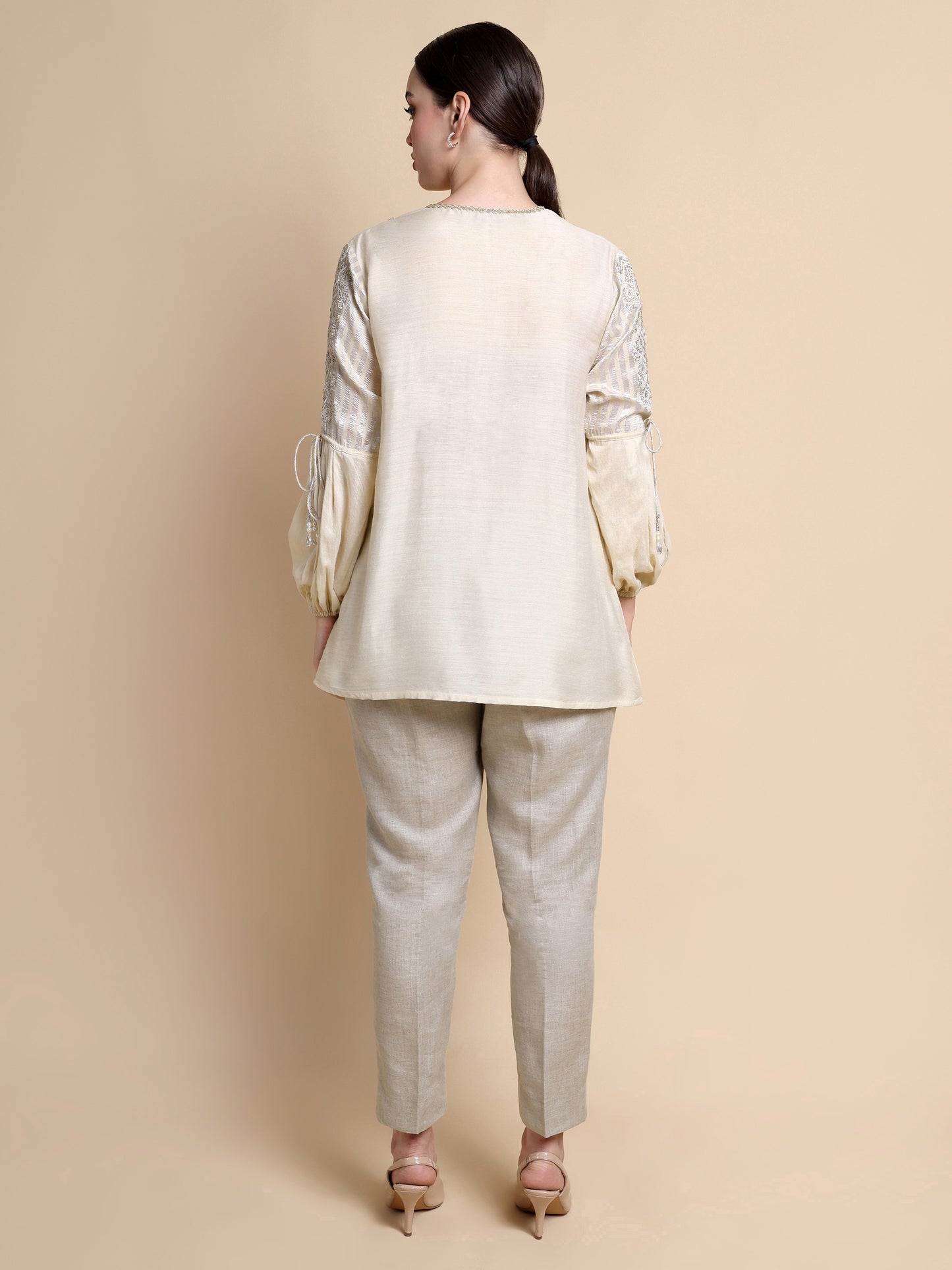 Woman wearing a beige traditional outfit with a plain background