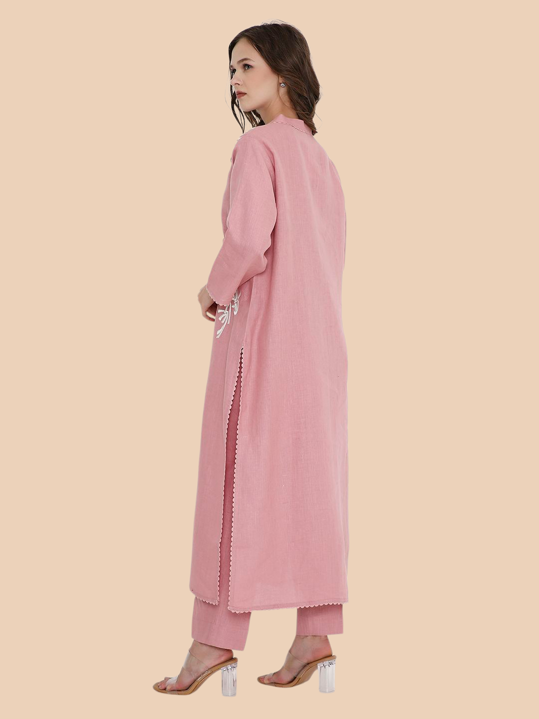 Woman wearing a long pink coat with a plain background