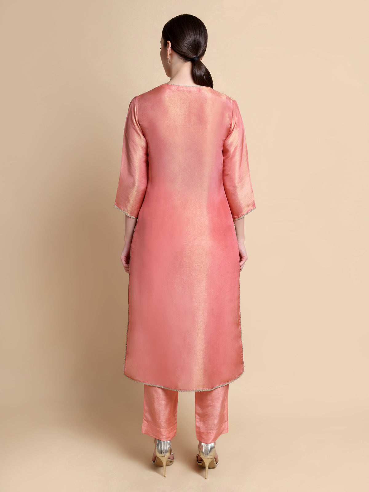 Woman wearing a pink kurta with pants on a beige background