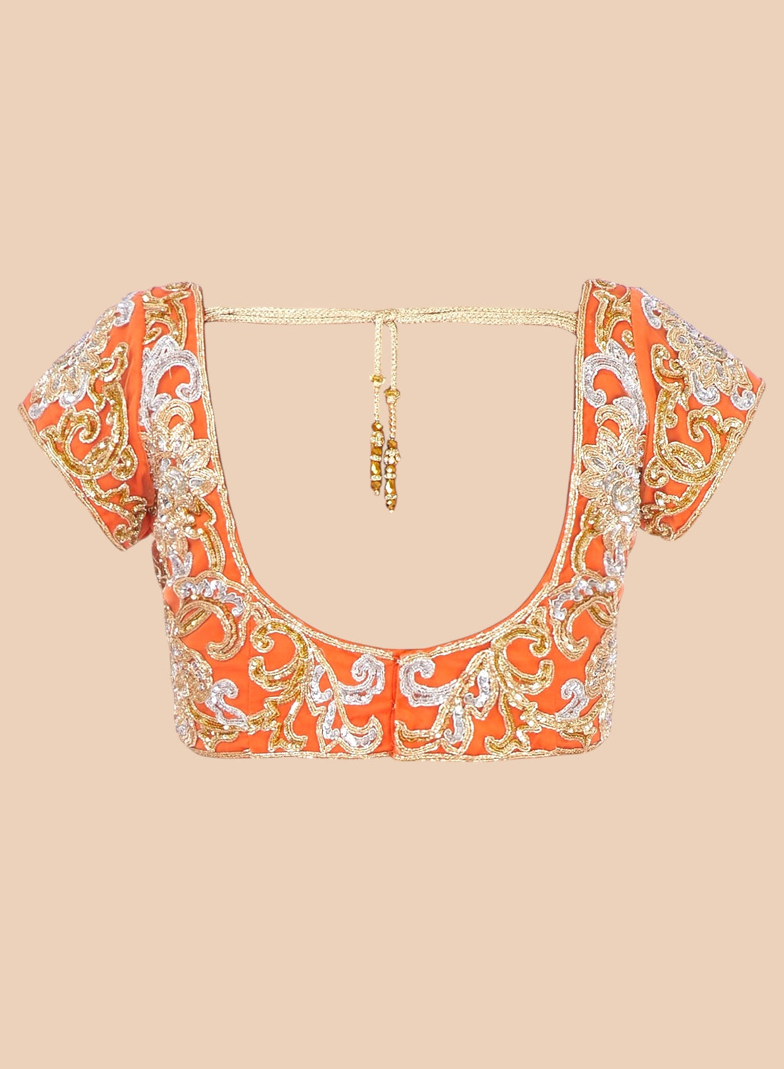 Orange embroidered blouse with gold and white details on a beige background
