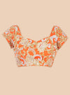 Orange floral patterned top on a beige background
