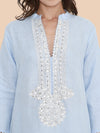 Light blue shirt with intricate white embroidery on a beige background