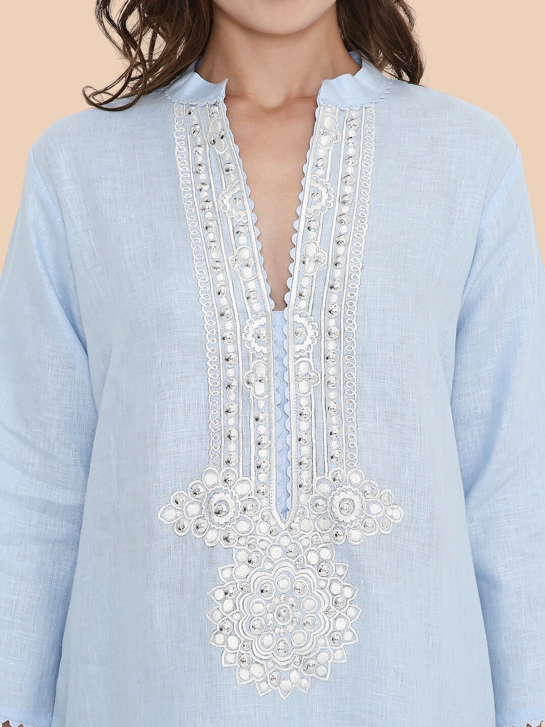 Light blue shirt with intricate white embroidery on a beige background