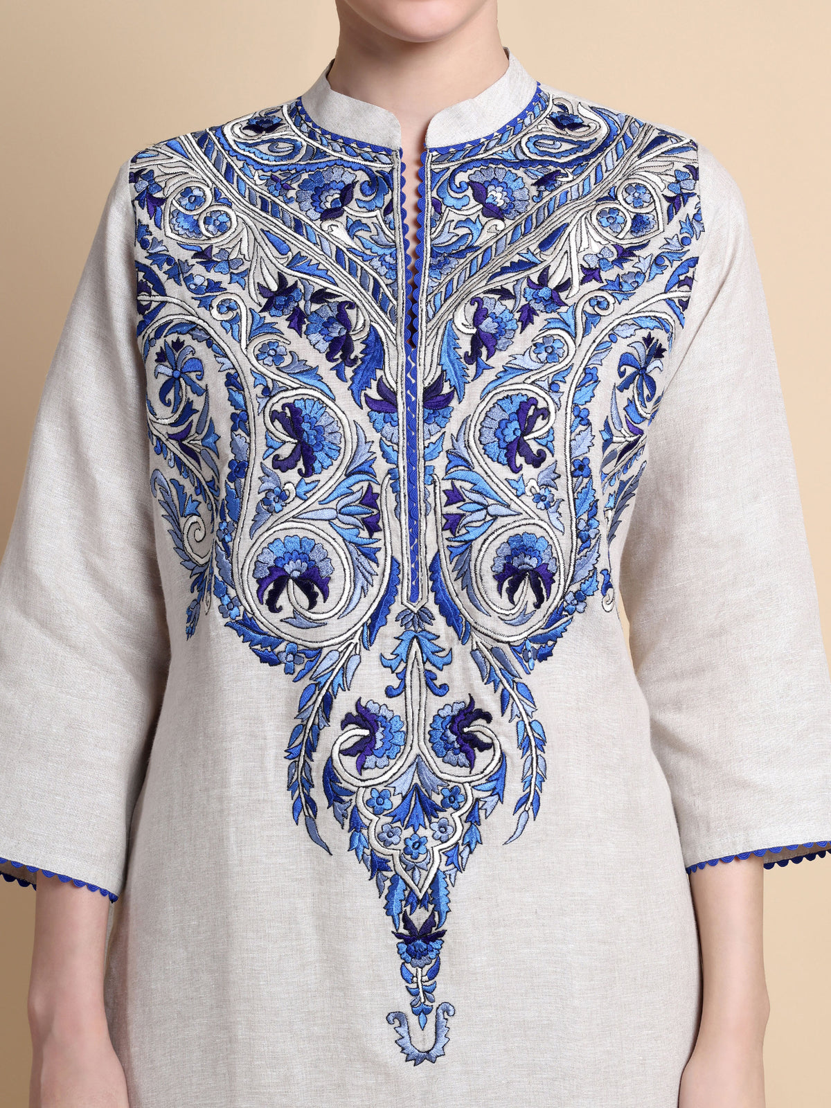 White kurta with blue intricate embroidery on a beige background