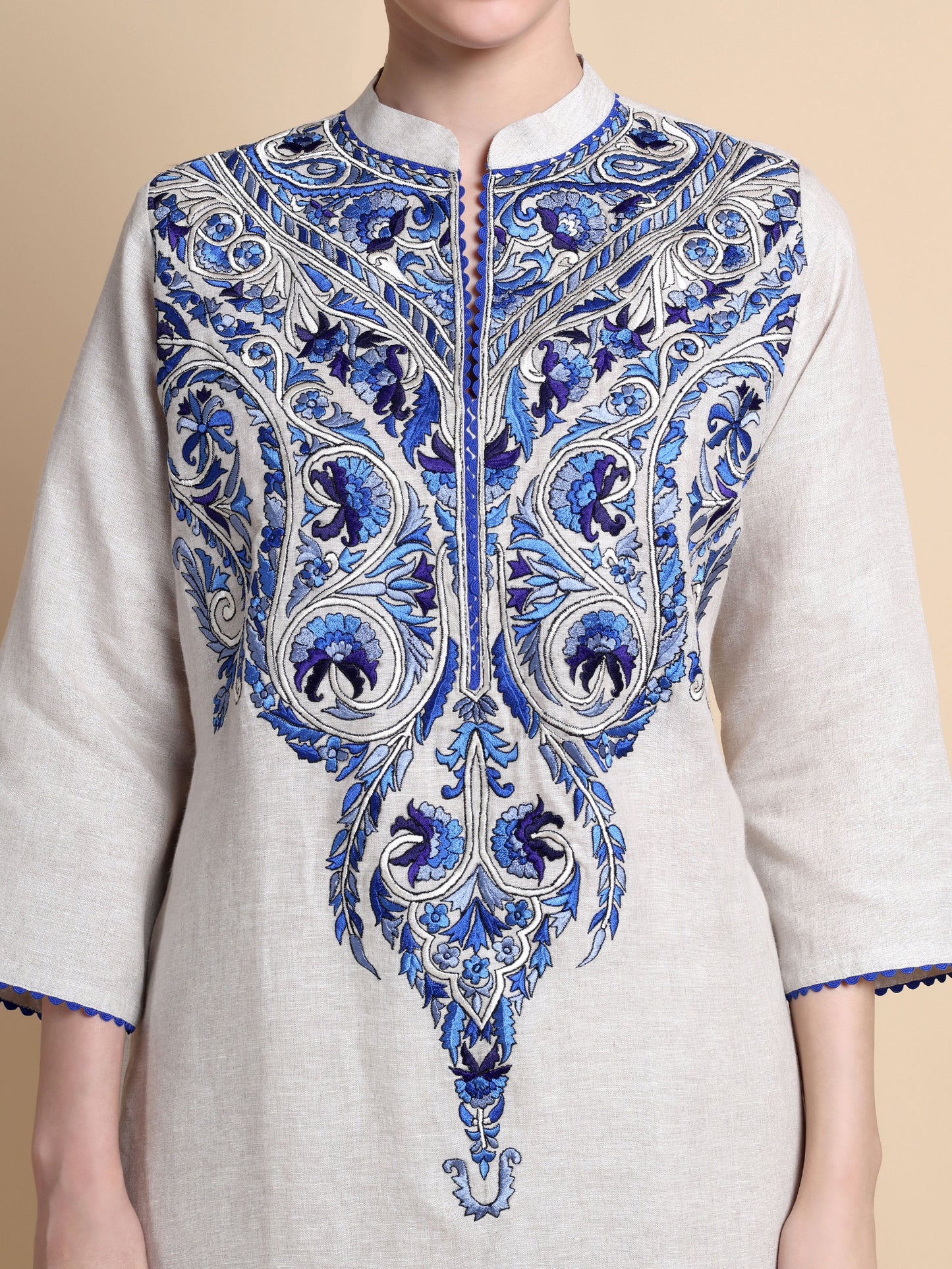 White kurta with blue intricate embroidery on a beige background
