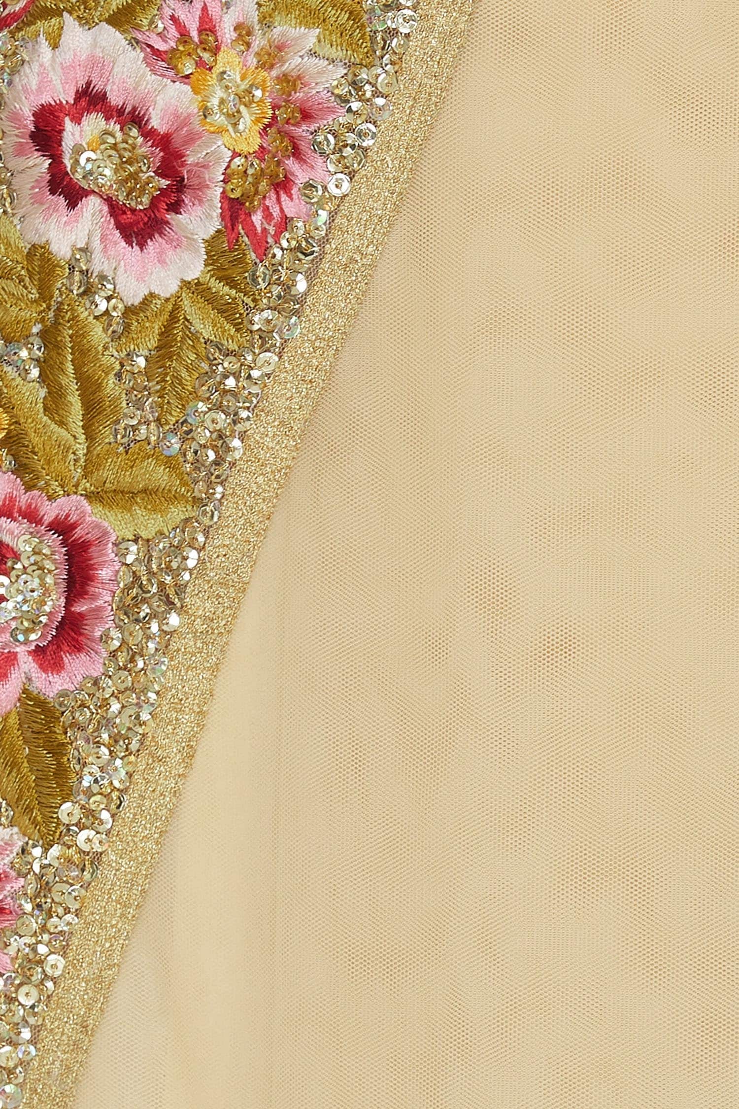Close-up of embroidered fabric with floral patterns and beads on a beige background