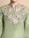 Green embroidered top with pink flowers on a beige background