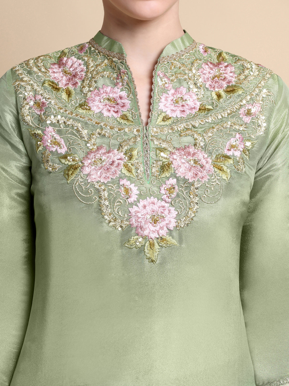 Green embroidered top with pink flowers on a beige background