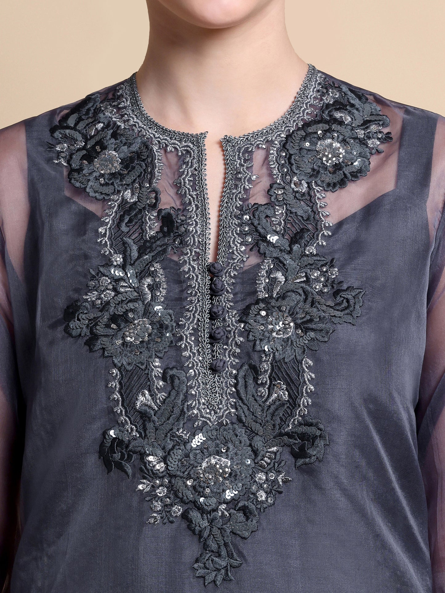 Dark gray sleeveless top with intricate floral embroidery on a beige background