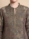 Brown embroidered garment with intricate patterns on a beige background