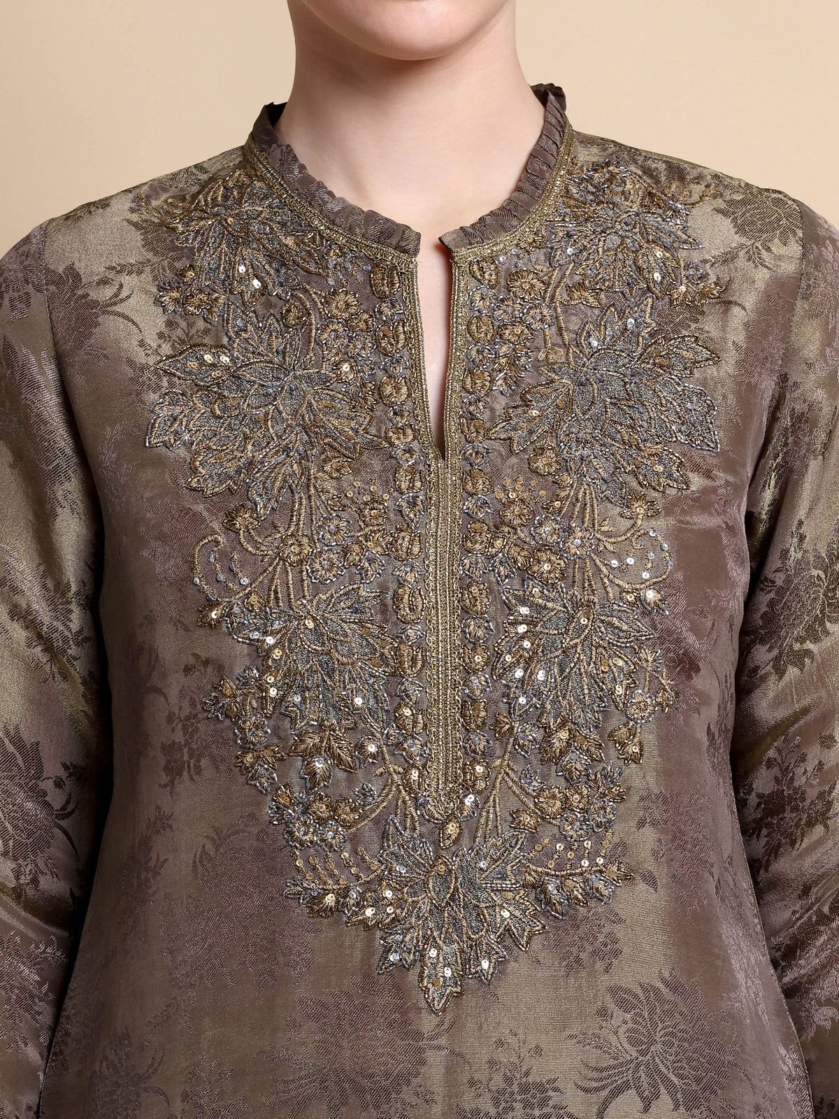 Brown embroidered garment with intricate patterns on a beige background