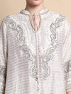 White embroidered shirt with intricate patterns on a beige background