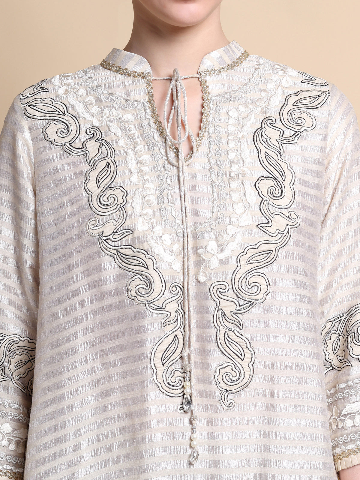 White embroidered shirt with intricate patterns on a beige background
