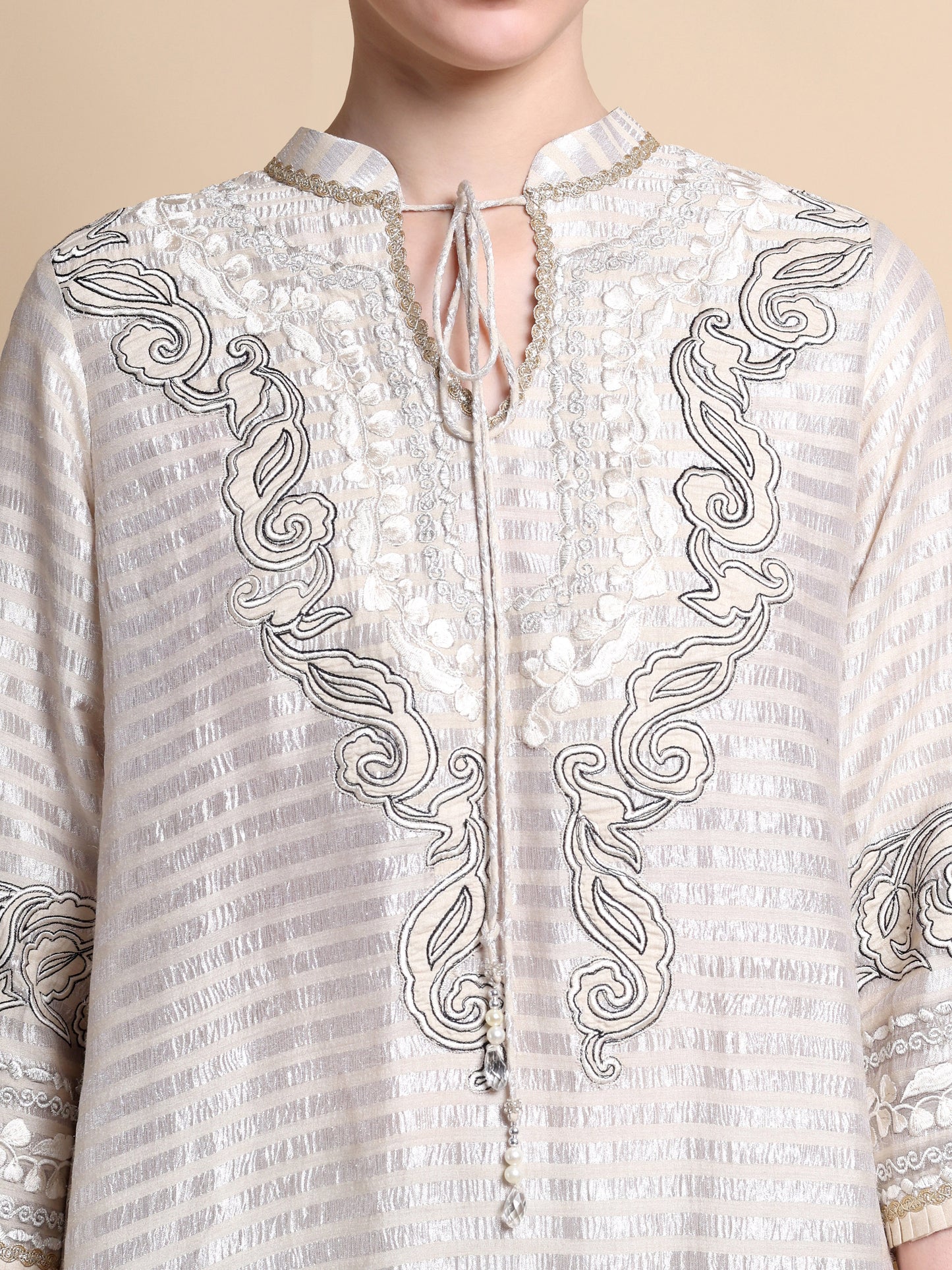 White embroidered shirt with intricate patterns on a beige background