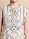 Close-up of a sleeveless top with intricate beadwork on a neutral background