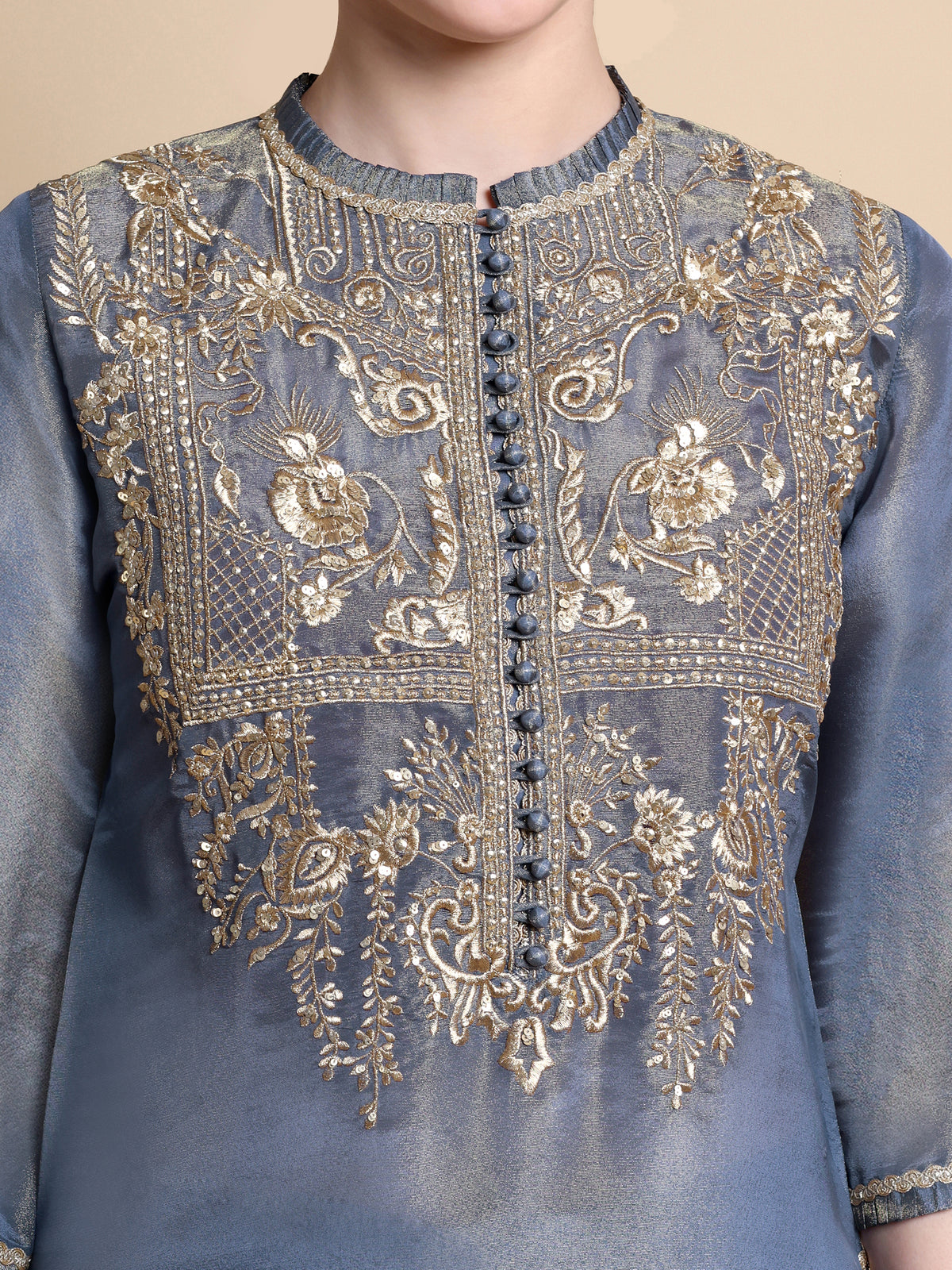 Blue embroidered garment with gold details on a beige background