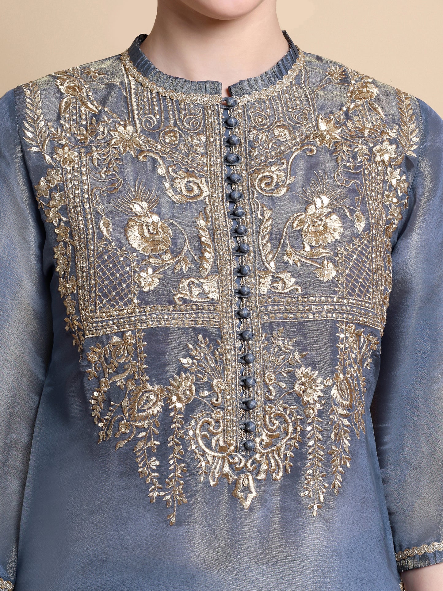 Blue embroidered garment with gold details on a beige background