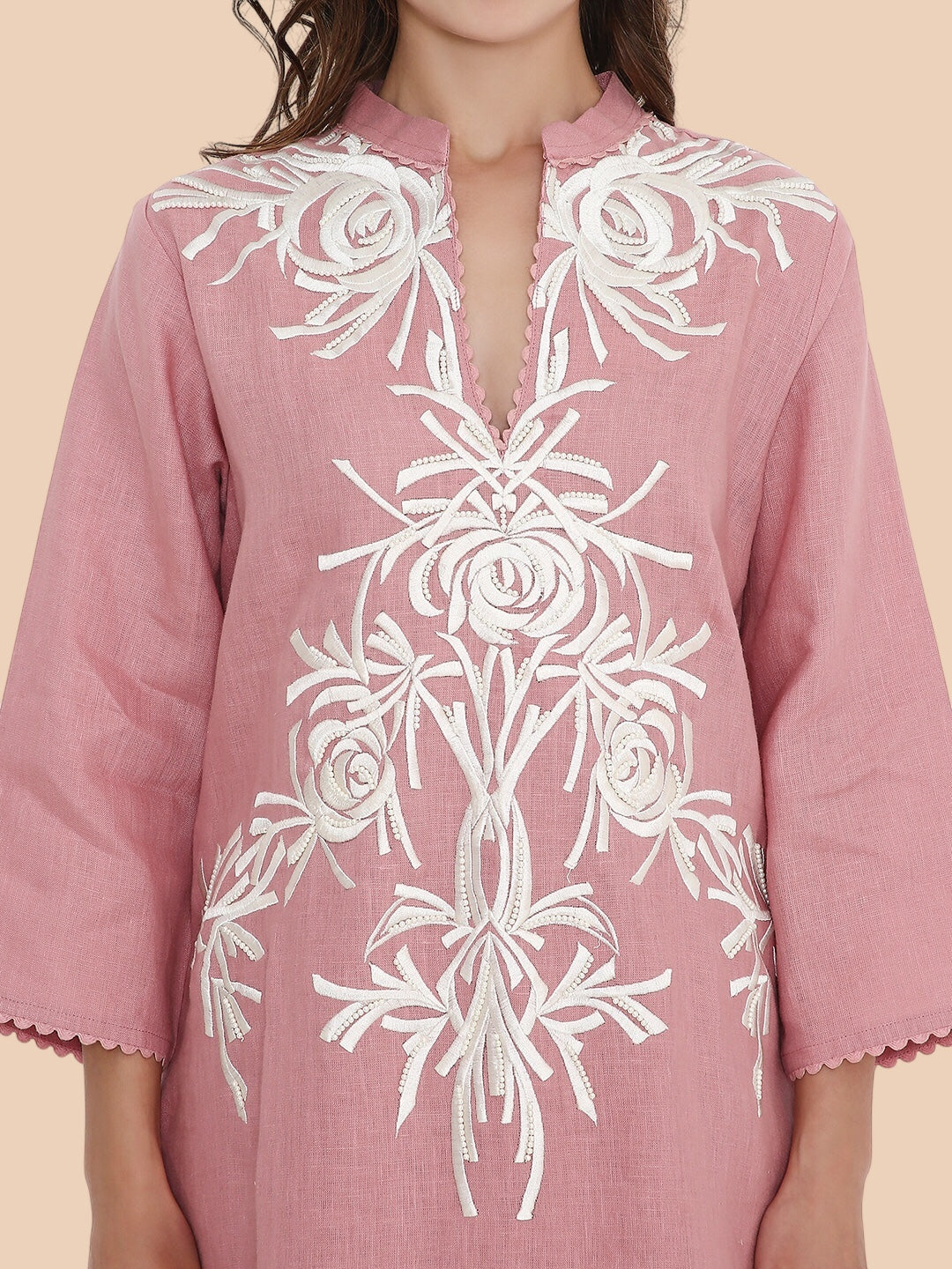 Pink kurta with white floral embroidery on a beige background