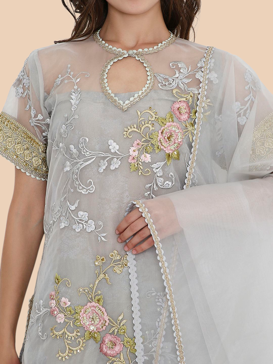 Gray embroidered dress with floral patterns and a pearl necklace on a beige background