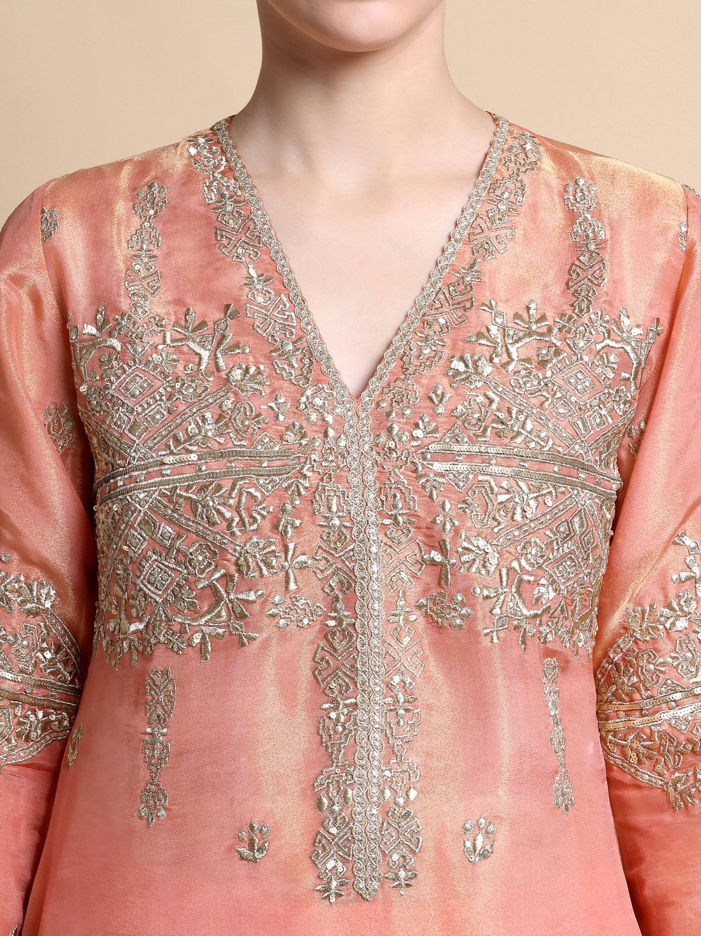 Close-up of a pink embroidered garment with intricate silver detailing.