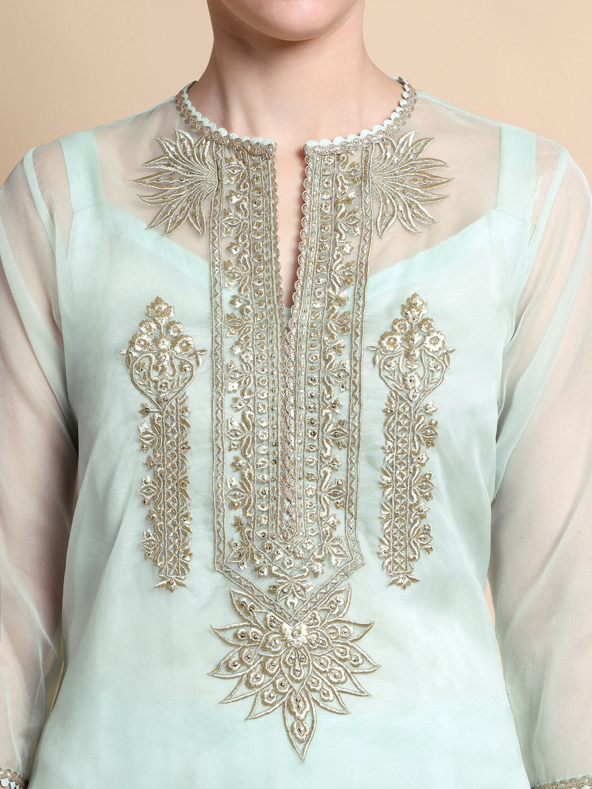 Light blue embroidered top with intricate gold patterns on a beige background