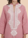 Pink embroidered dress with white patterns on a beige background