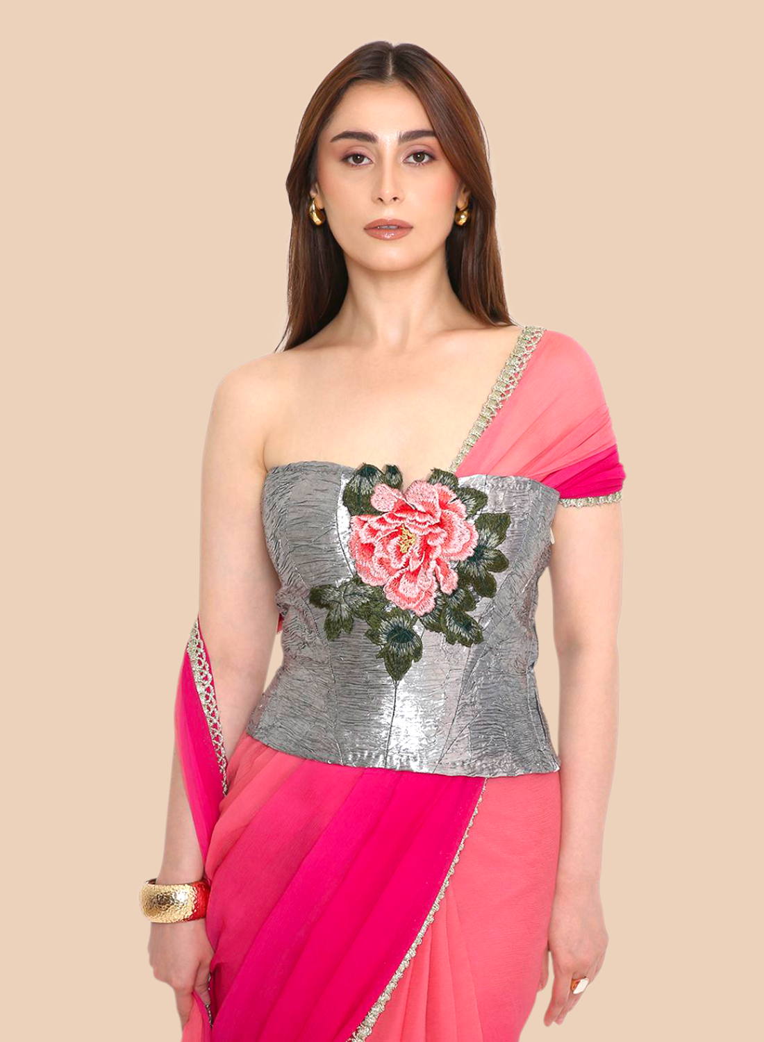 Woman wearing a pink corset with a silver blouse featuring floral design on a beige background