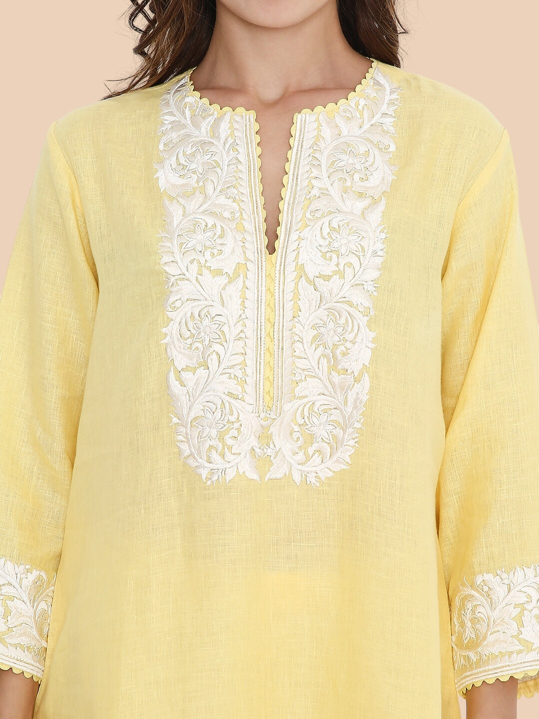Yellow kurta with white lace details on a beige background